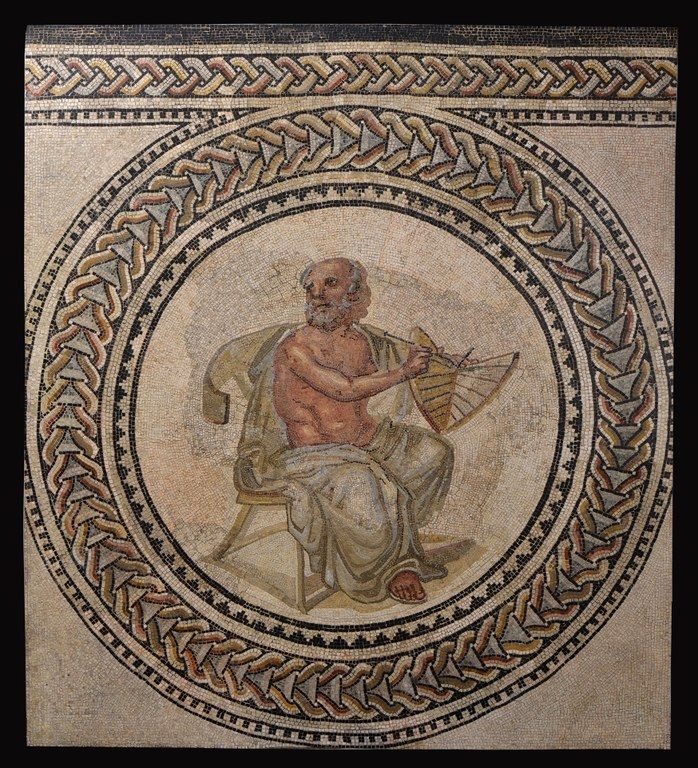 Mosaic roundel of a balding, bearded man seated on a chair, holding a sundial
