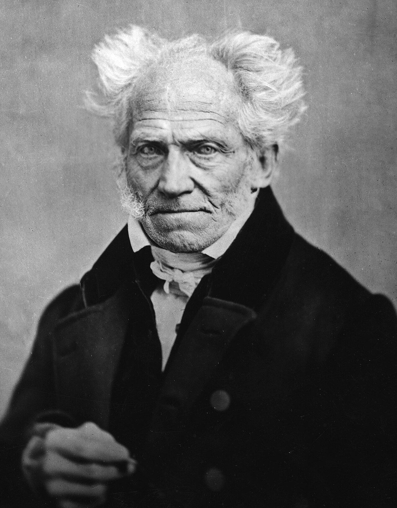 Photograph of an elderly man with white hair brushed out at the sides and a stern expression
