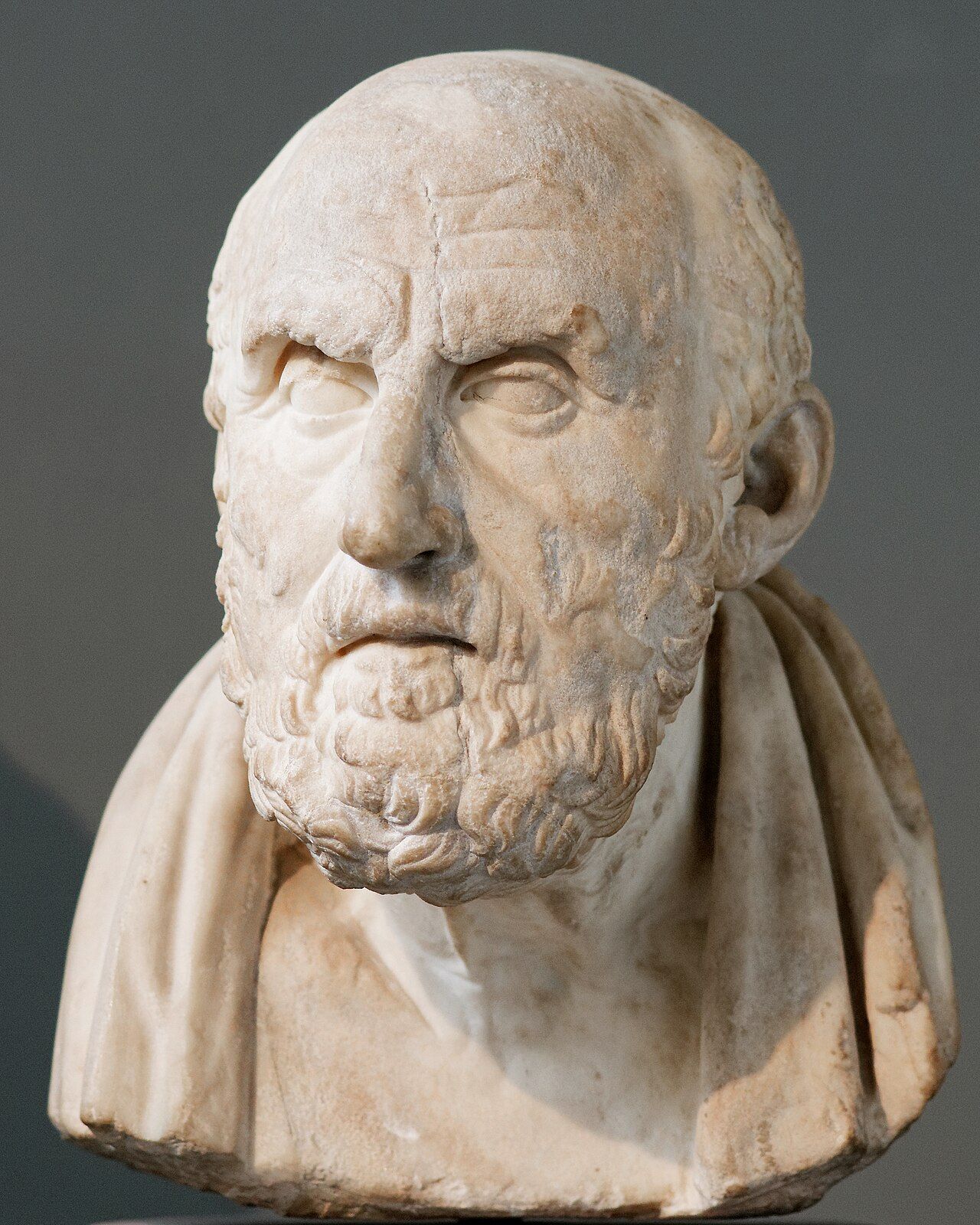 Marble bust of an old, frowning man with a balding head and a curly beard