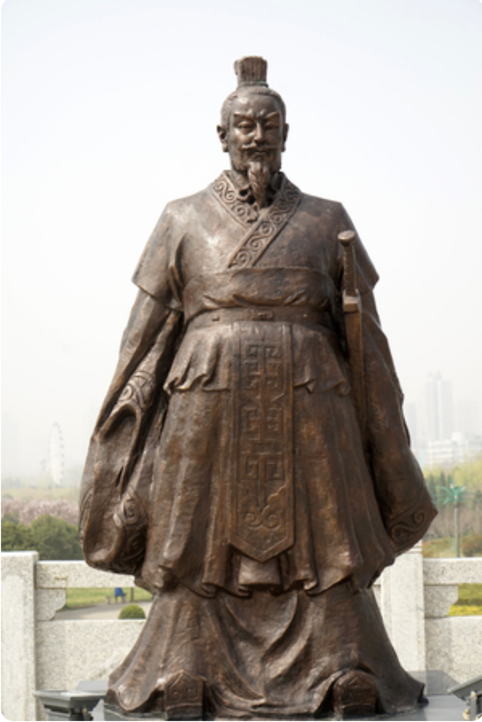 Bronze statue of a robed man with a beard and a tall cap