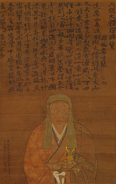 Painted portrait of a seated monk in a patterned robe and hood, beneath columns of Chinese calligraphy
