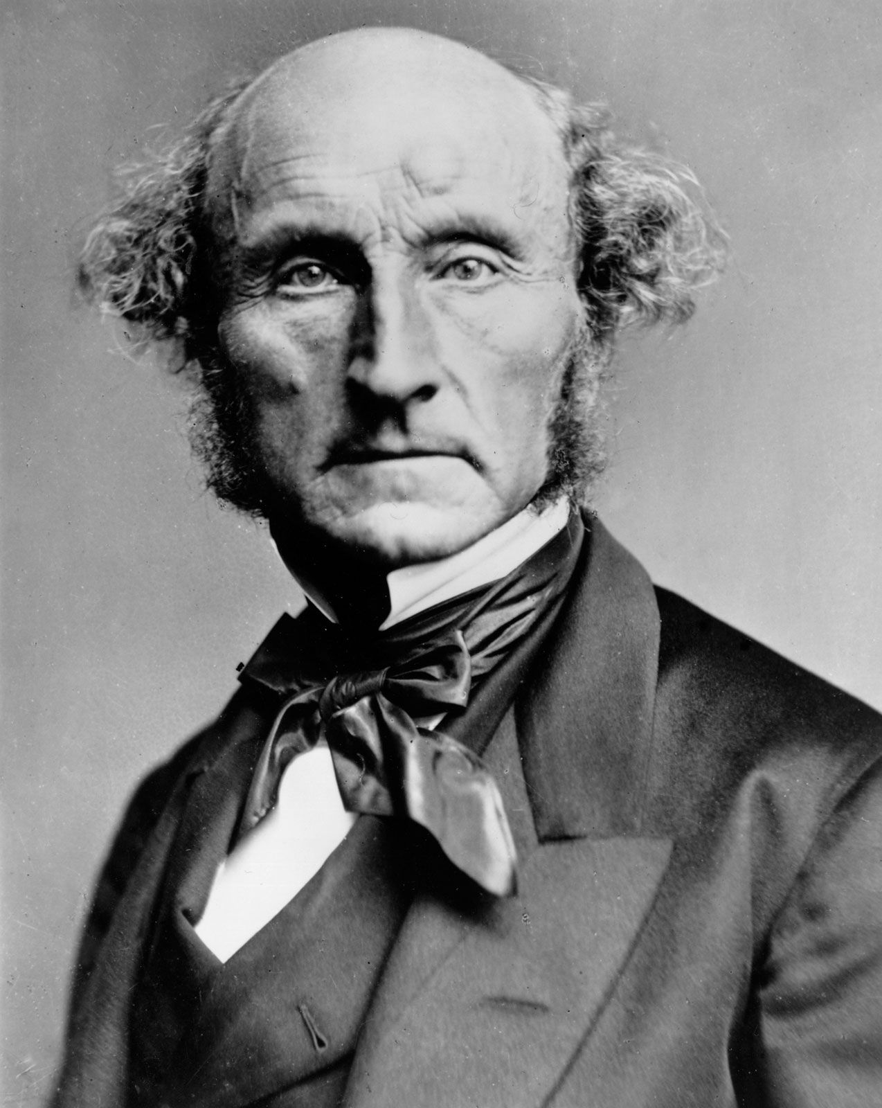 Photograph of a balding man with side-whiskers in a dark coat and bow tie