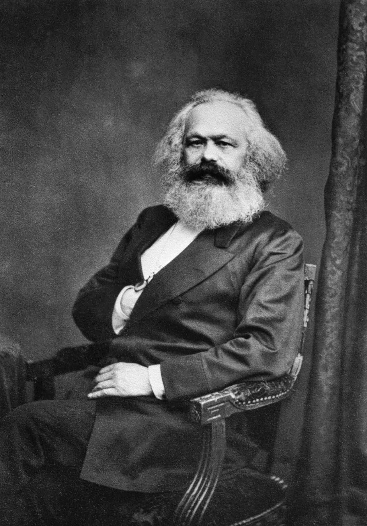 Photograph of a seated man with a full white beard and swept-back hair