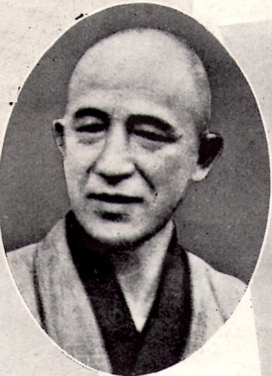 Black-and-white photograph of a man with a shaven head in a dark kimono, in an oval frame