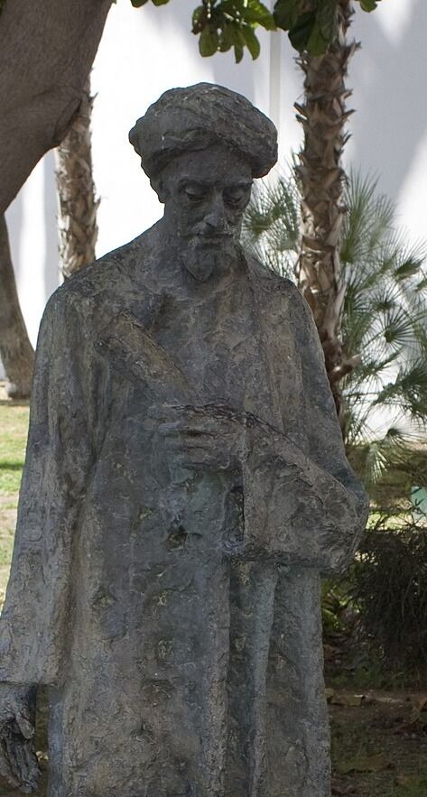 Statue of a bearded man in a turban and long robe, holding a book