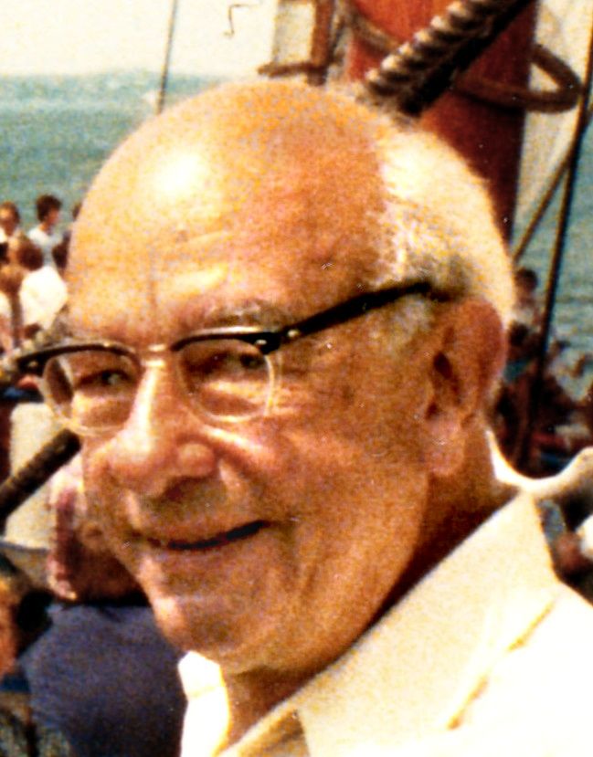Colour photograph of a smiling bald man in glasses on the deck of a sailing ship